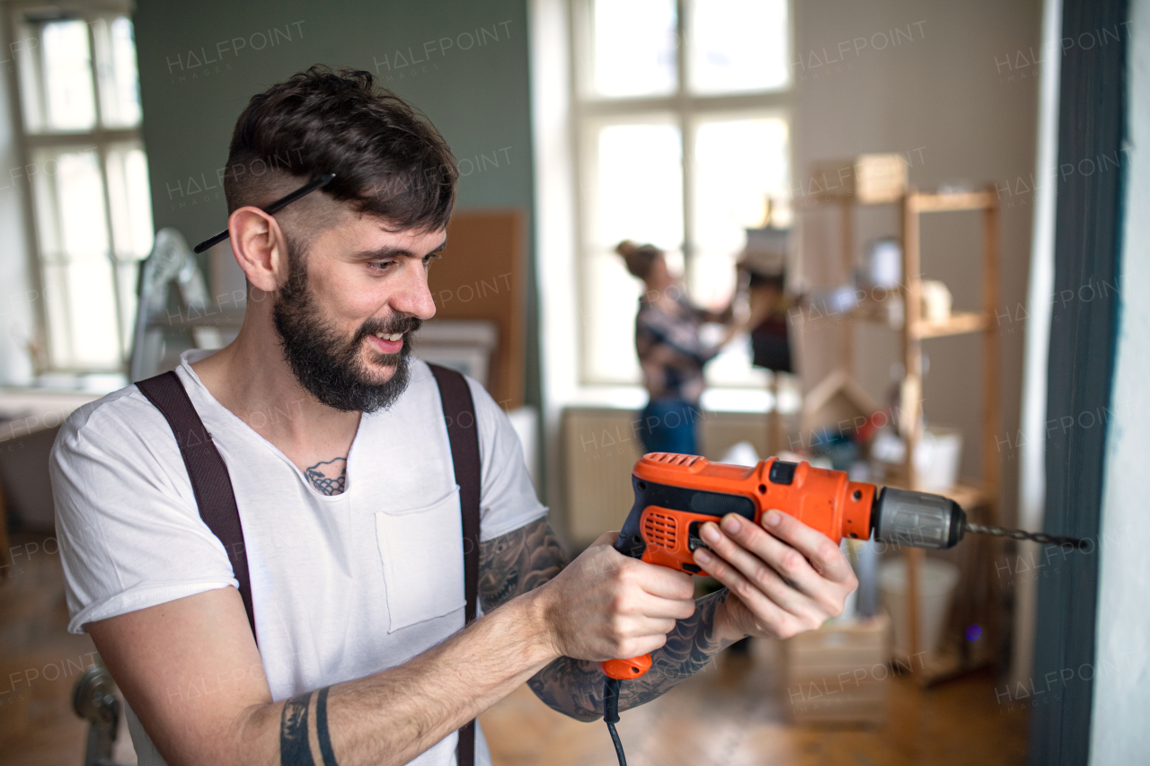 Man with electric drill working indoors at home, relocation and diy concept.