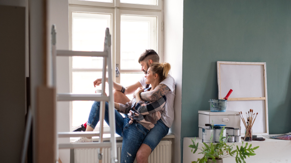 Mid adults couple sitting and resting indoors at home, relocation and diy concept.