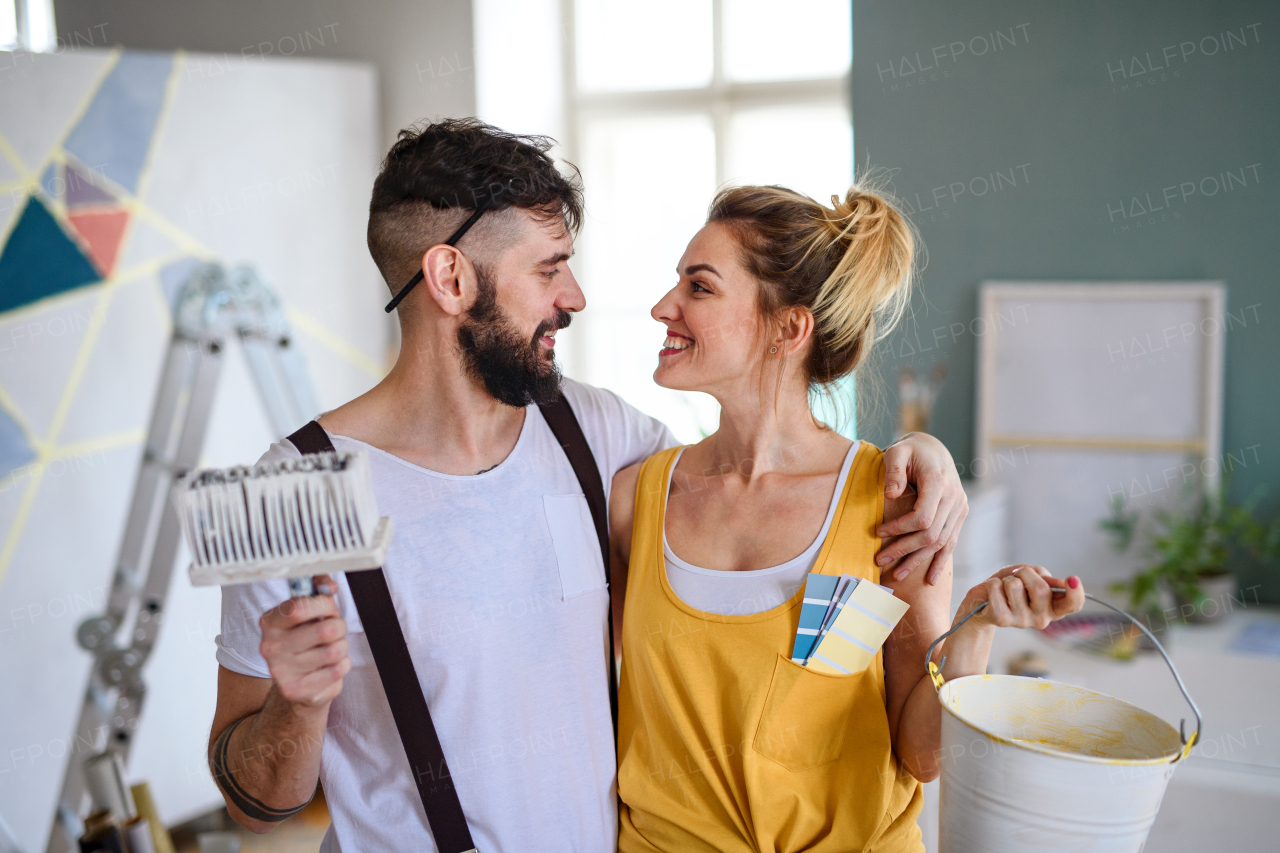 Mid adults couple having fun when painting wall indoors at home, relocation and diy concept.