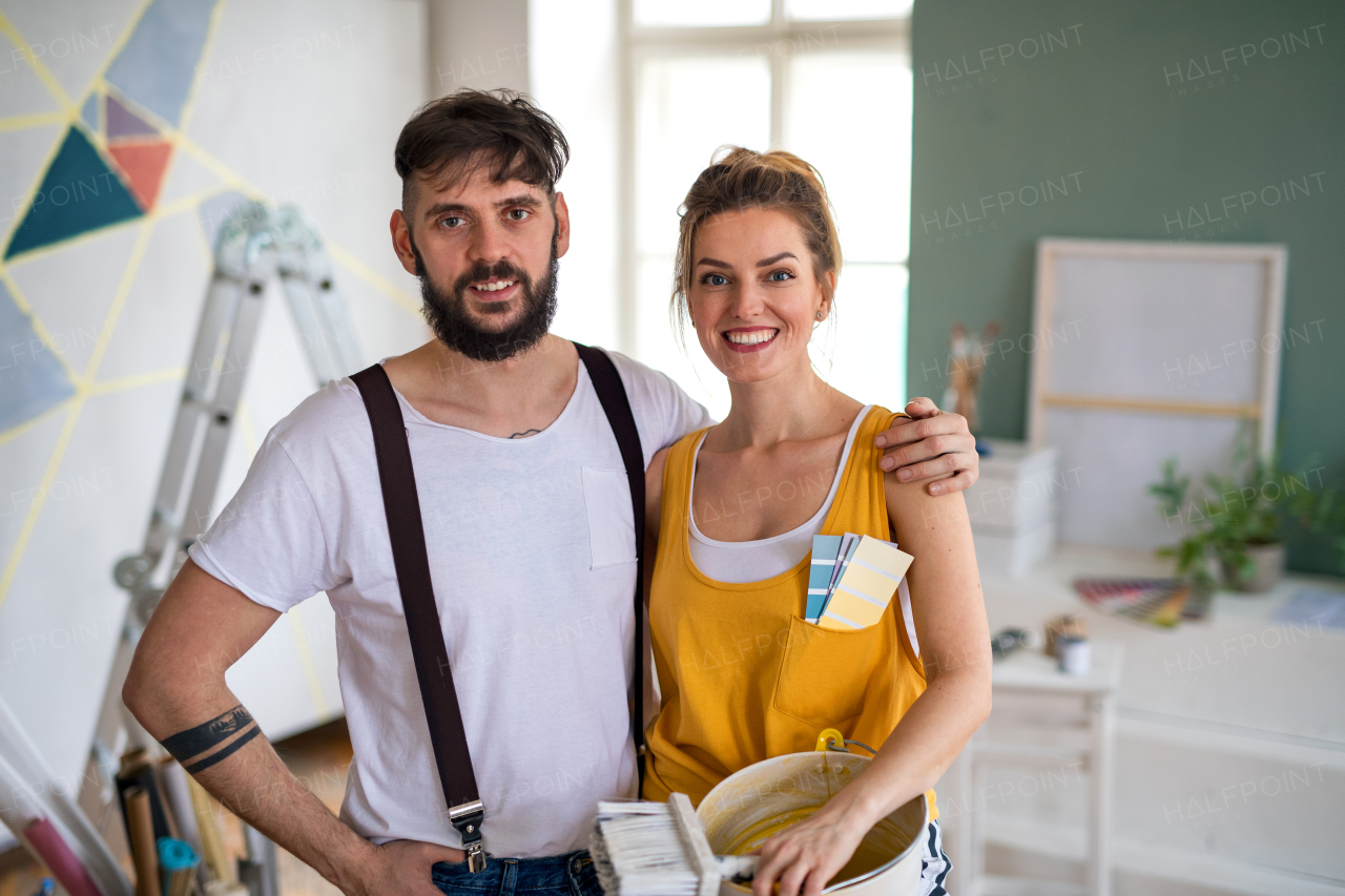 Portrait of couple looking at camera indoors at home, relocation, painting and diy concept.