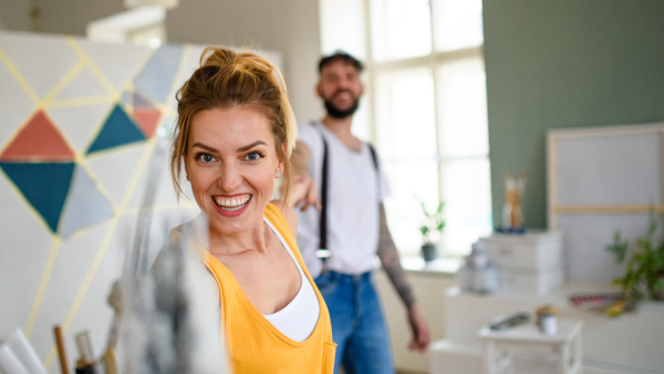 Mid adults couple having fun when painting wall indoors at home, relocation and diy concept.