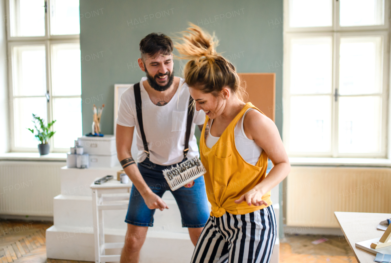 Mid adults couple having fun when painting wall indoors at home, relocation and diy concept.