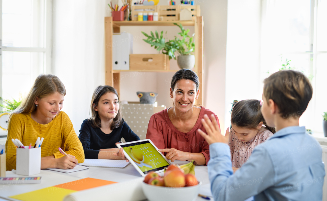 Group of homeschooling children with parent teacher studying indoors, coronavirus concept.