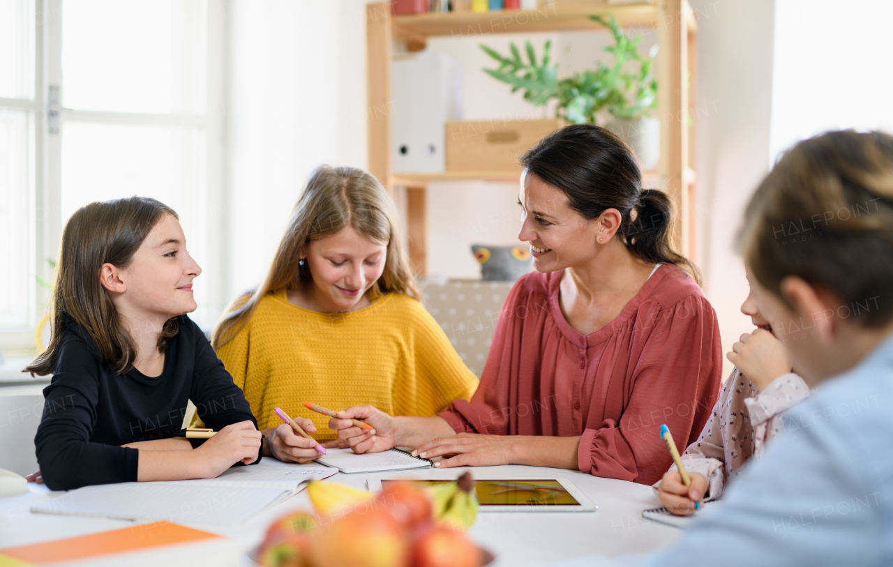 Group of homeschooling children with parent teacher studying indoors, coronavirus concept.