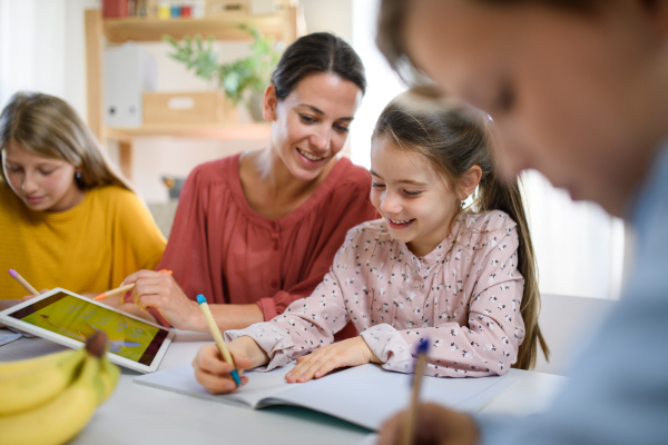 Group of homeschooling children with parent teacher studying indoors, coronavirus concept.