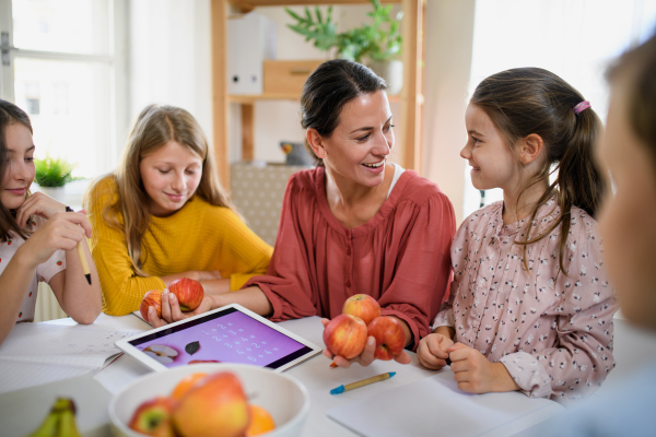 Group of homeschooling children with parent teacher studying indoors, coronavirus concept.