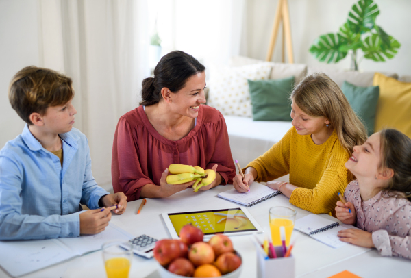 Group of homeschooling children with parent teacher studying indoors, coronavirus concept.