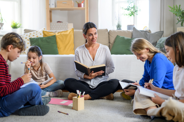 Group of homeschooling children with parent teacher studying indoors, coronavirus concept.