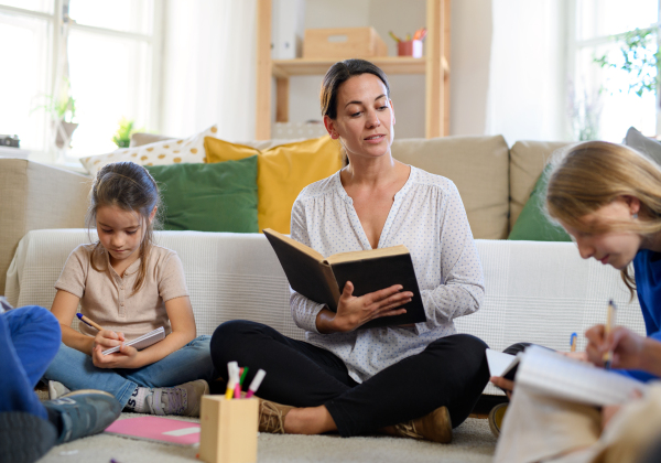 Group of homeschooling children with parent teacher studying indoors, coronavirus concept.