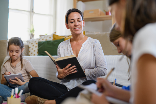 Group of homeschooling children with parent teacher studying indoors, coronavirus concept.