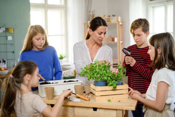 Group of homeschooling children with parent teacher planting herbs indoors, coronavirus concept.