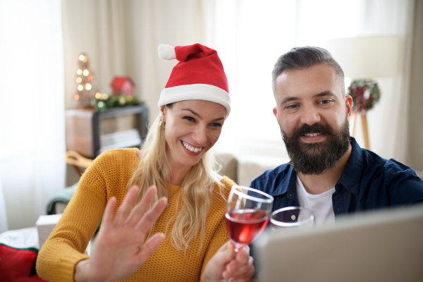 Front view of happy couple indoors at home at Christmas, having video call with family or friends.