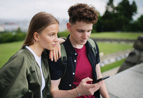 Portrait of young couple travelers in city on holiday, using smartphone.