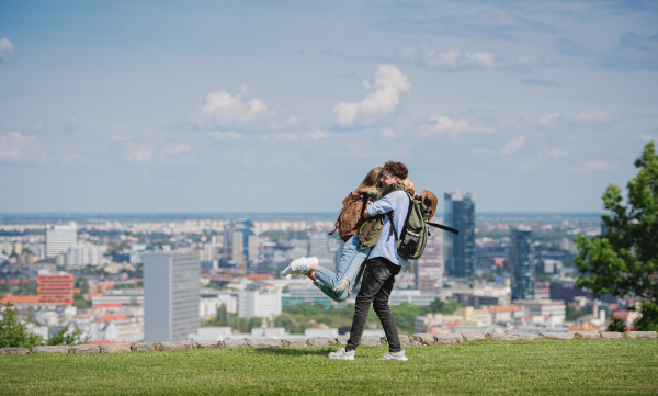 Happy young couple travelers in city on holiday, hugging. Cityscape in the background.