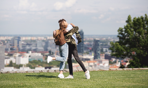 Happy young couple travelers in city on holiday, hugging. Cityscape in the background.