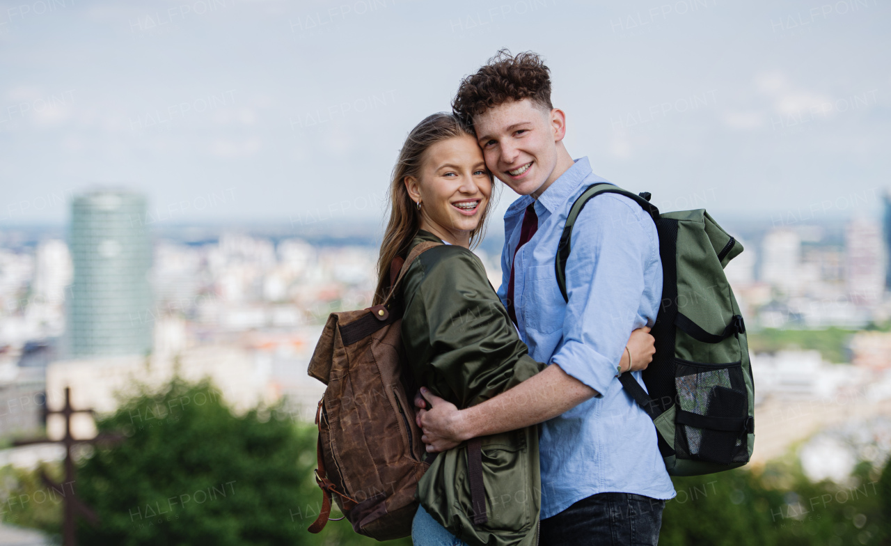 A young couple travelers in city on holiday, looking at camera. Cityscape in the background.