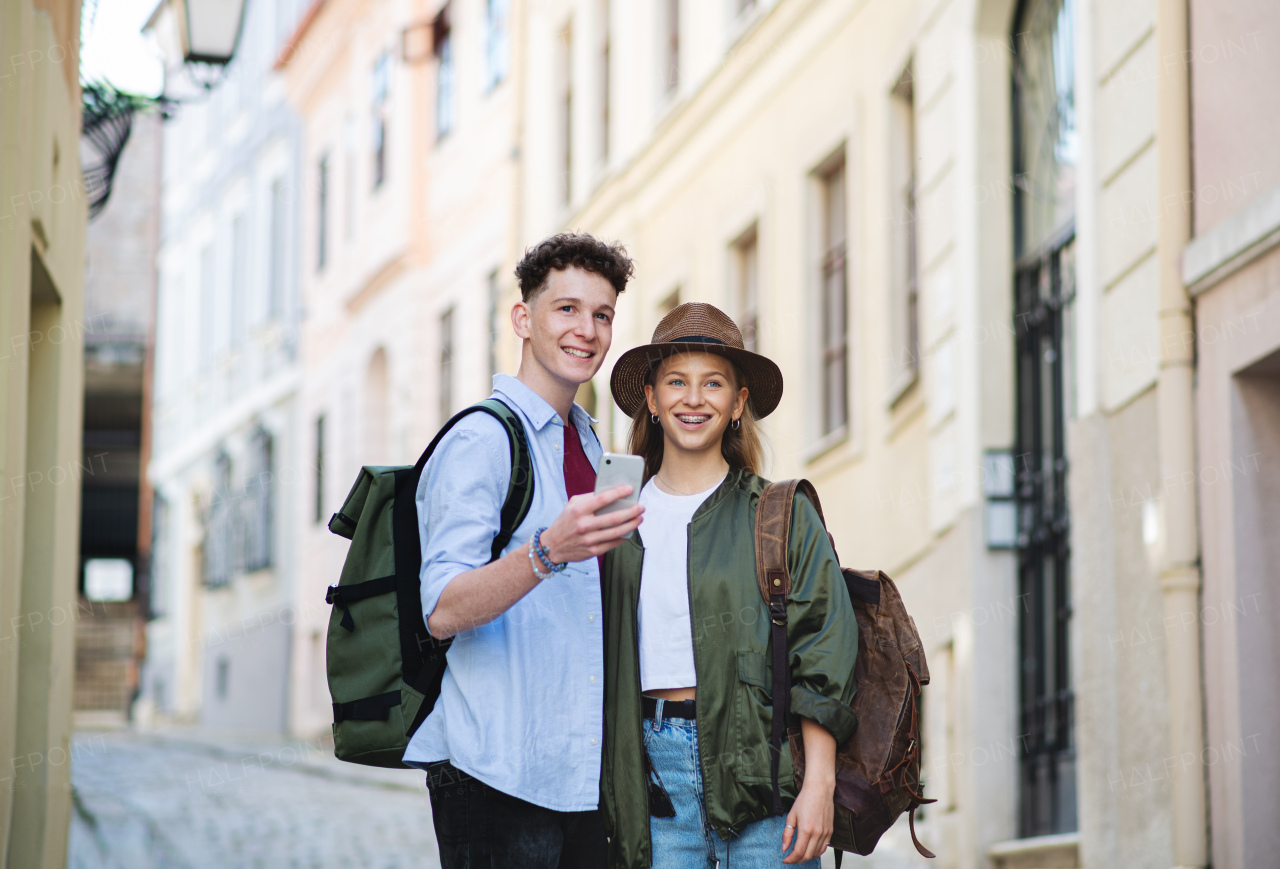 A young couple travelers using smartphone in city on holiday, sightseeing.