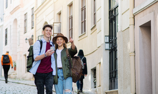 A young couple travelers using smartphone in city on holiday, sightseeing.