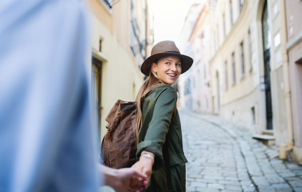 A young couple travelers in love sightseeing in city on holiday, holding hands when walking.