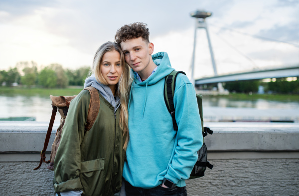 A happy young couple travelers in city on holiday, looking at camera.