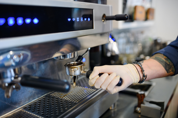 Unrecognizable barista working with gloves, coffee shop open after lockdown quarantine.