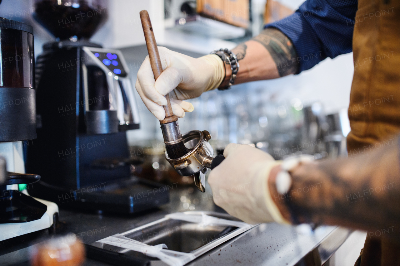 Unrecognizable barista working with gloves, coffee shop open after lockdown quarantine.