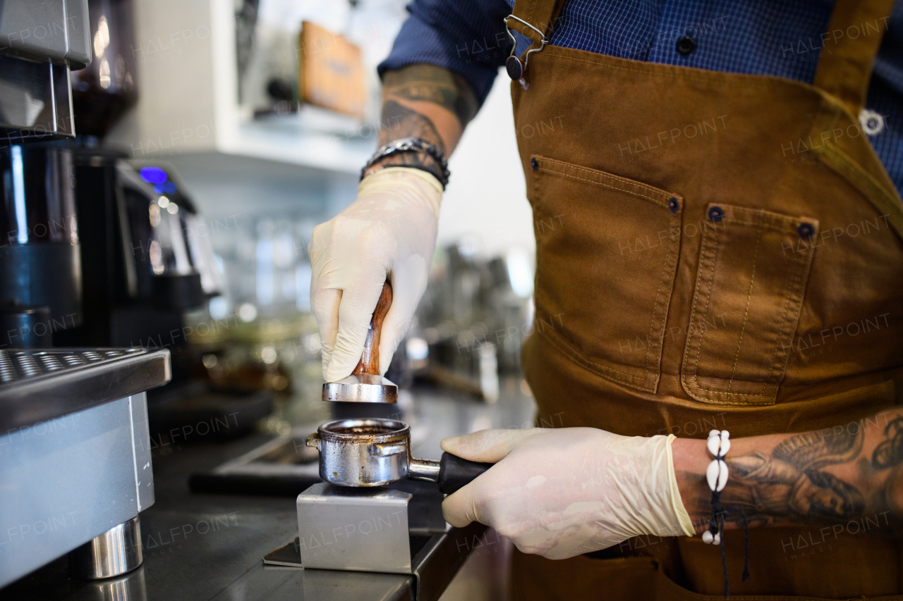 Unrecognizable barista working with gloves, coffee shop open after lockdown quarantine.