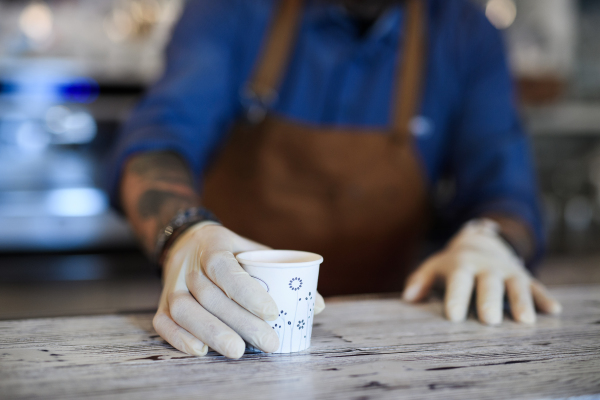 Unrecognizable barista working with gloves, coffee shop open after lockdown quarantine.