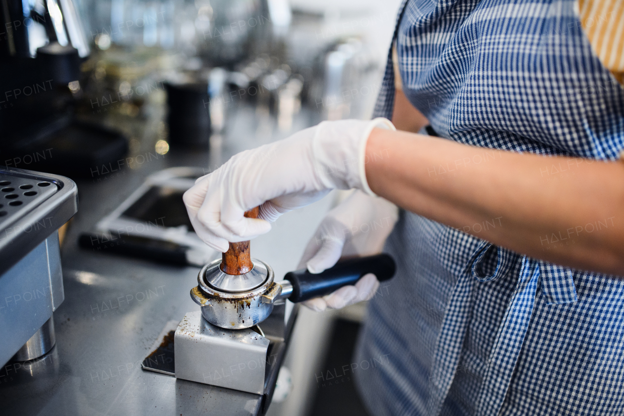 Midsection of unrecognizable woman working with gloves, coffee shop open after lockdown quarantine.