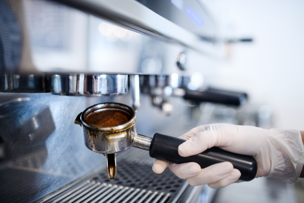 Close-up of unrecognizable barista working with gloves, coffee shop open after lockdown quarantine.