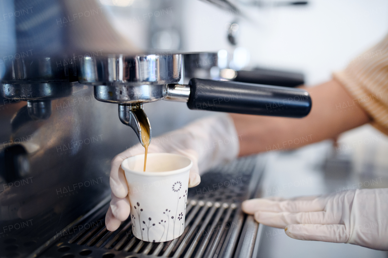 Midsection of unrecognizable woman working with gloves, coffee shop open after lockdown quarantine.