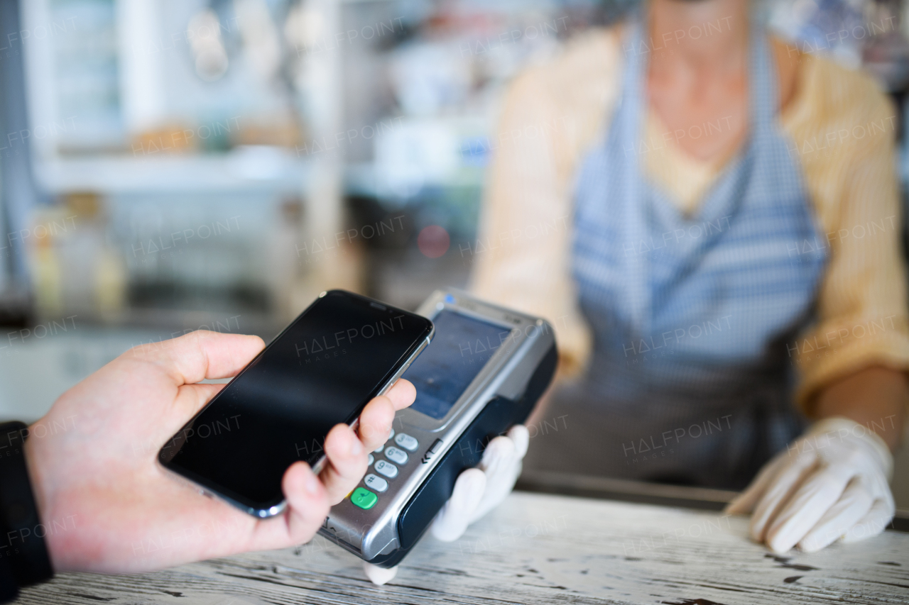 Contactless payment with smartphone, coffee shop open after lockdown. Midsection.