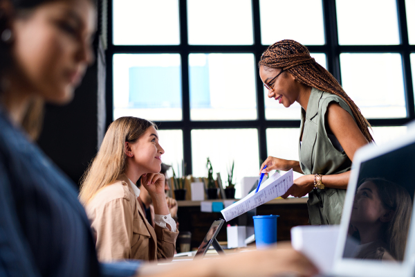 Side view portrait of young businesspeople working indoors in office, talking.