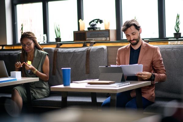 Front view portrait of young businesspeople working indoors in office, sitting.