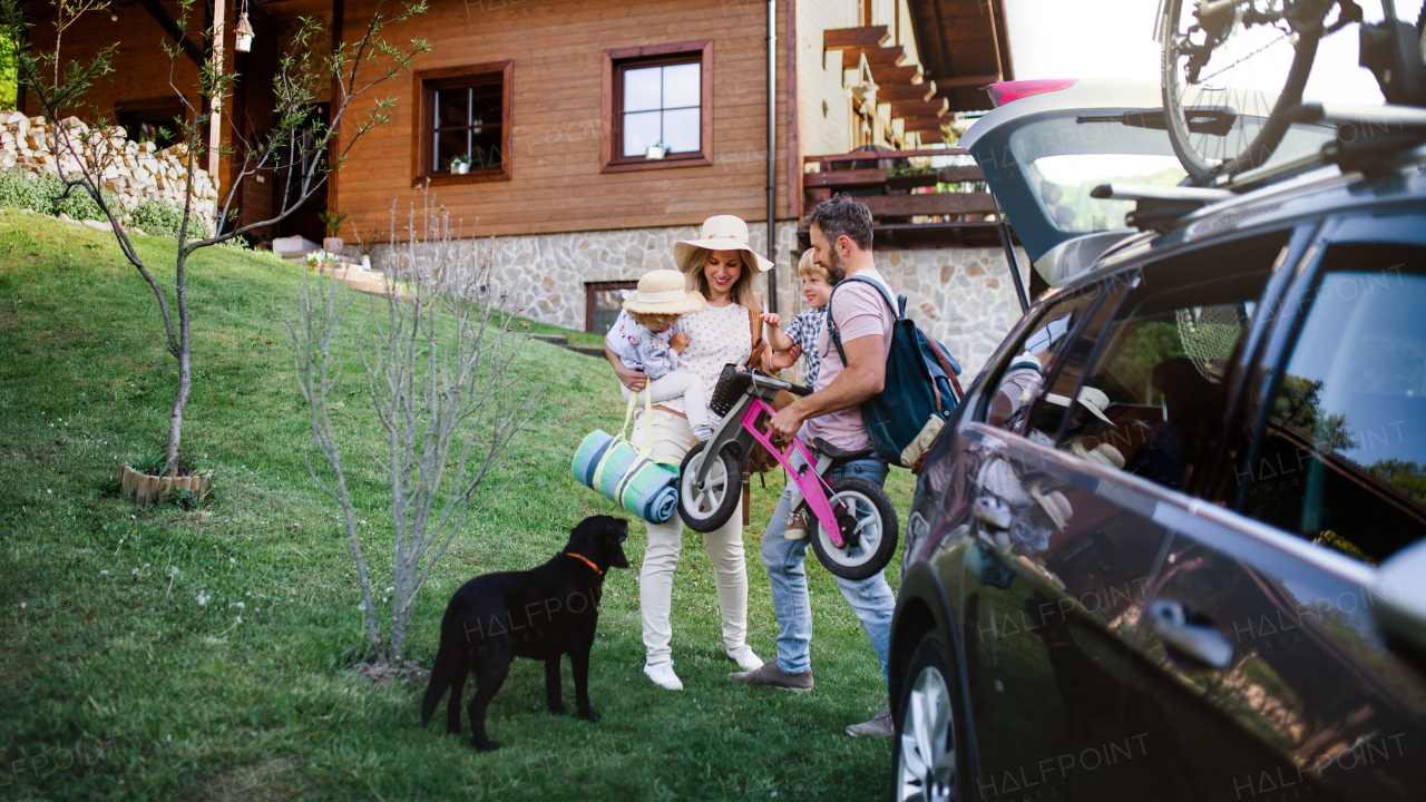 Family with two small children and dog going on cycling trip by car in countryside.