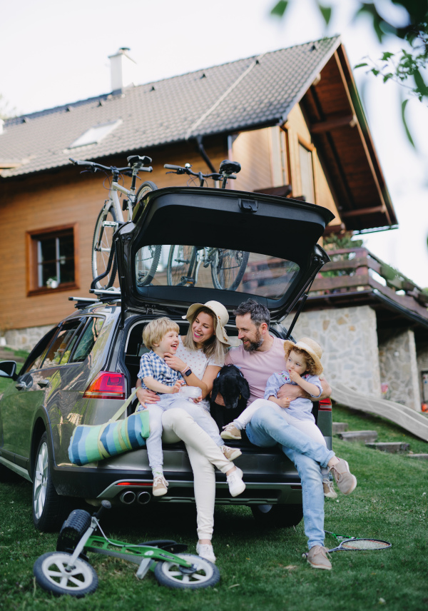 Family with two small children and dog going on cycling trip by car in countryside.