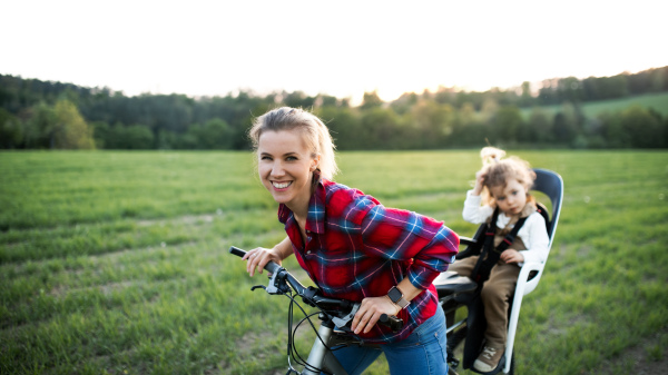 Happy mother with two small daughter on cycling trip, having fun.