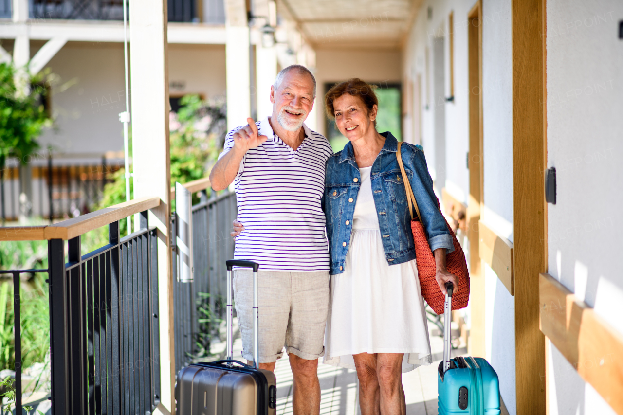 Senior couple with luggage outside apartment on holiday, back to normal concept.