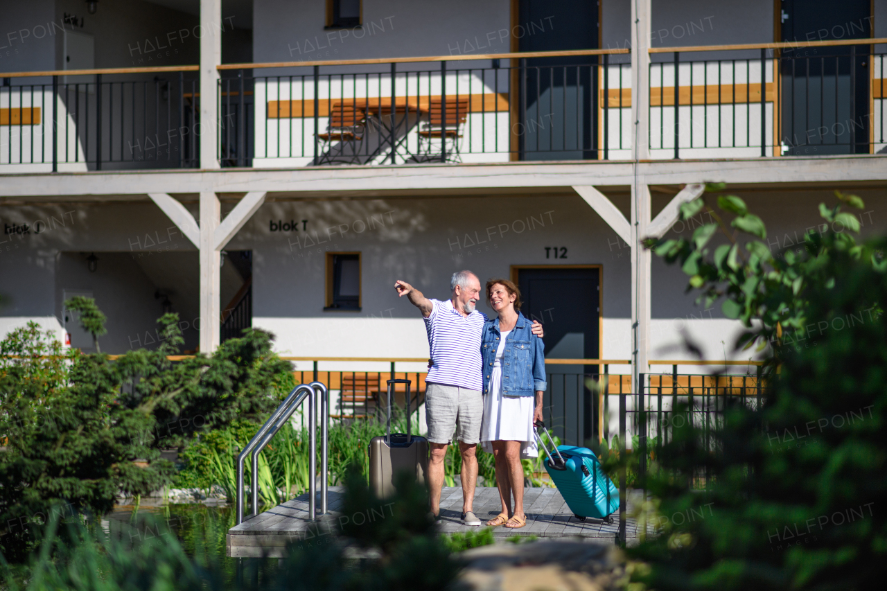 Senior couple with luggage outside apartment on holiday, back to normal concept.