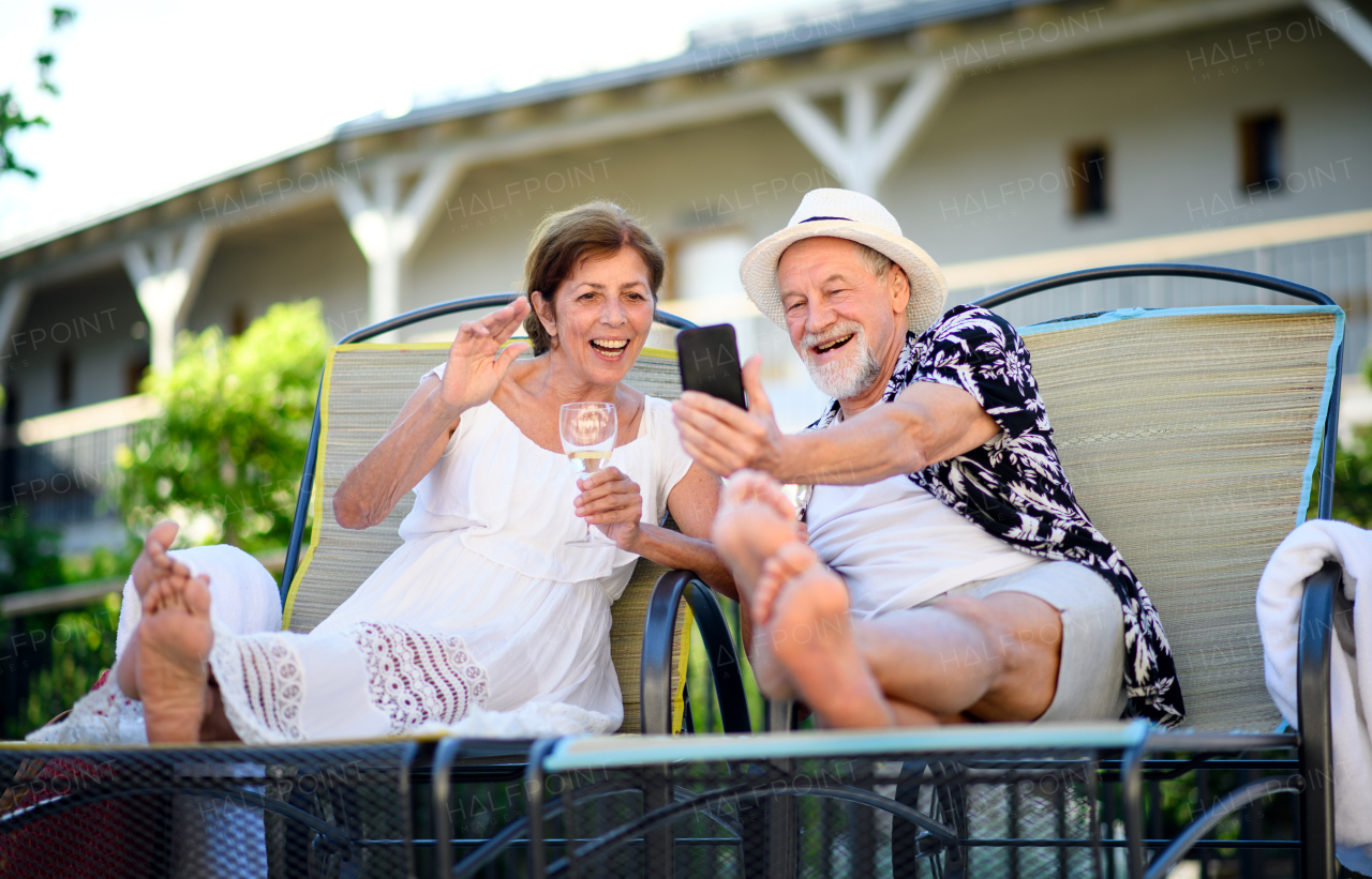 Cheerful senior couple with smartphone outdoors on holiday, video call concept.