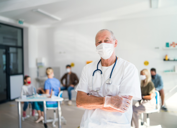 Portrait of senior doctor with face mask looking at camera, coronavirus, covid-19 and vaccination concept.