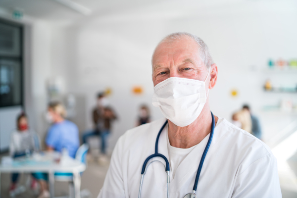 Portrait of senior doctor with face mask looking at camera, coronavirus, covid-19 and vaccination concept.