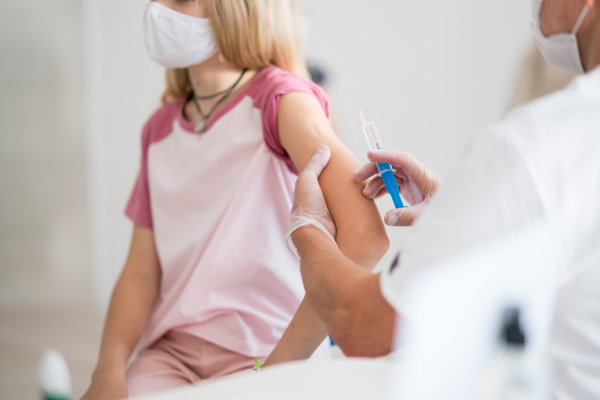 Midsection of child with face mask getting vaccinated, coronavirus, covid-19 and vaccination concept. Close-up.