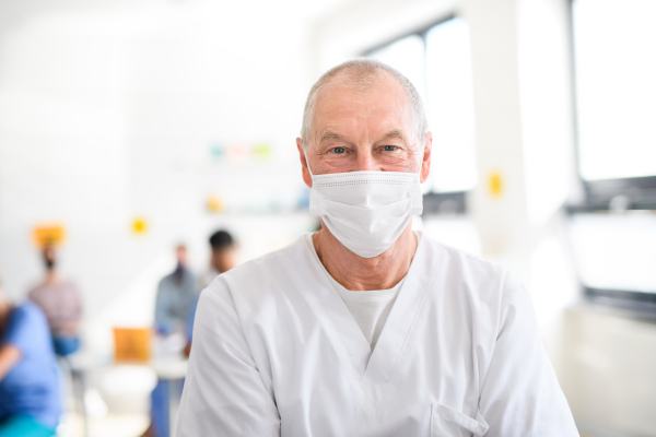 Portrait of senior doctor with face mask looking at camera, coronavirus, covid-19 and vaccination concept.