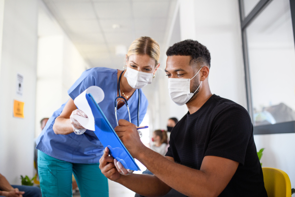 Portrait of nurse and man with face masks, coronavirus, covid-19 and vaccination concept, signing.