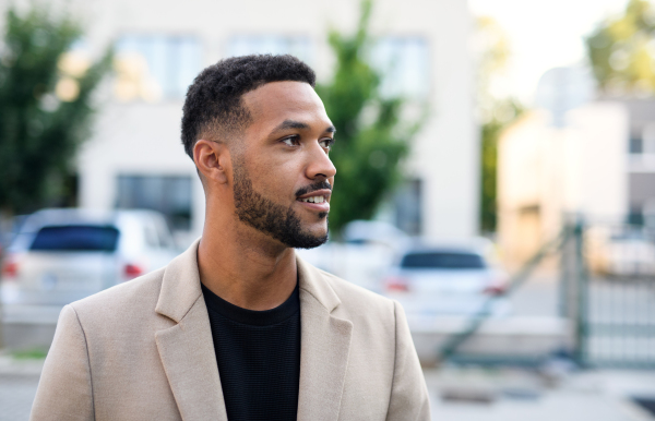 Front view portrait of african-american man standing outdoors in city.