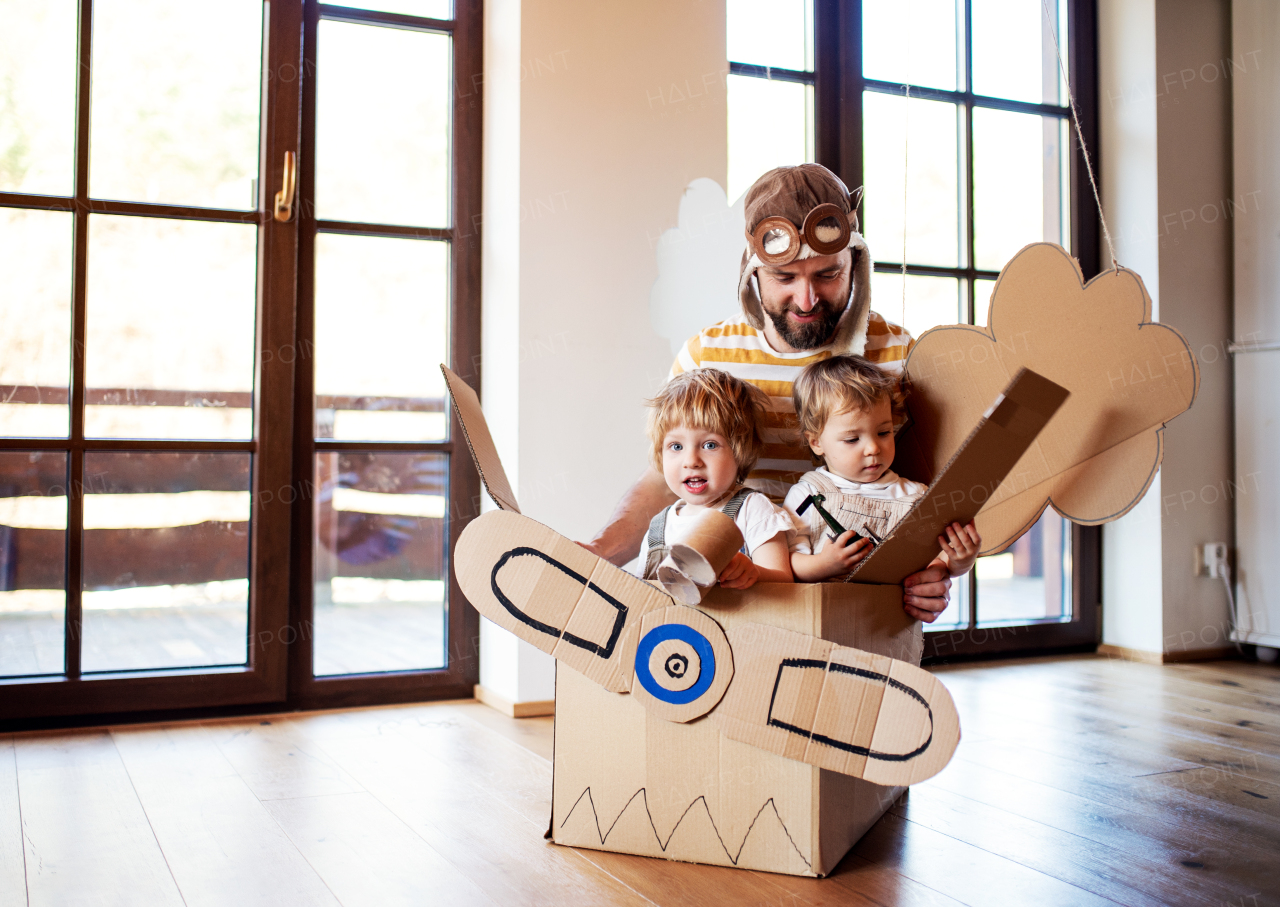 A father and toddler chidlren playing with carton plane indoors at home, flying concept.