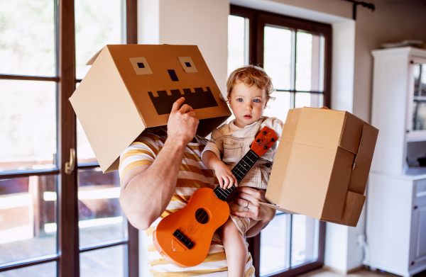 A happy toddler girl with a father and carboard monster playing indoors at home.