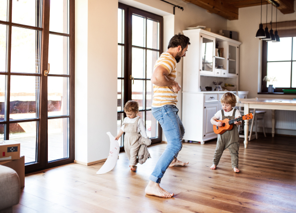 A father and toddler children playing indoors at home, having fun.