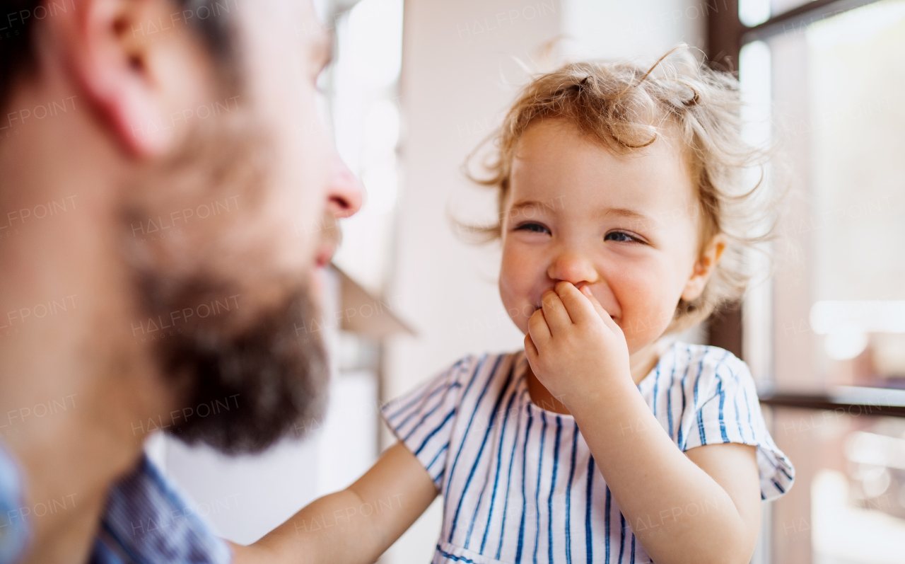 Mature father with small daughter playing indoors at home, a close-up.